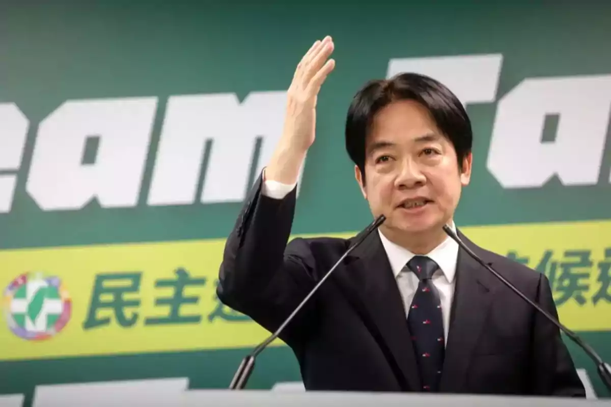 Man in a suit speaking at a podium with microphones and a green background with letters and symbols. Man in a suit speaking at a podium with microphones and a green background with letters and symbols.