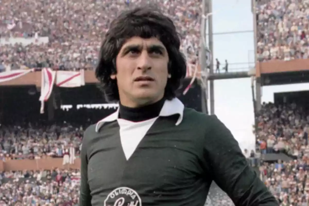 Portero de fútbol con uniforme verde en un estadio lleno de aficionados Portero de fútbol con uniforme verde en un estadio lleno de aficionados