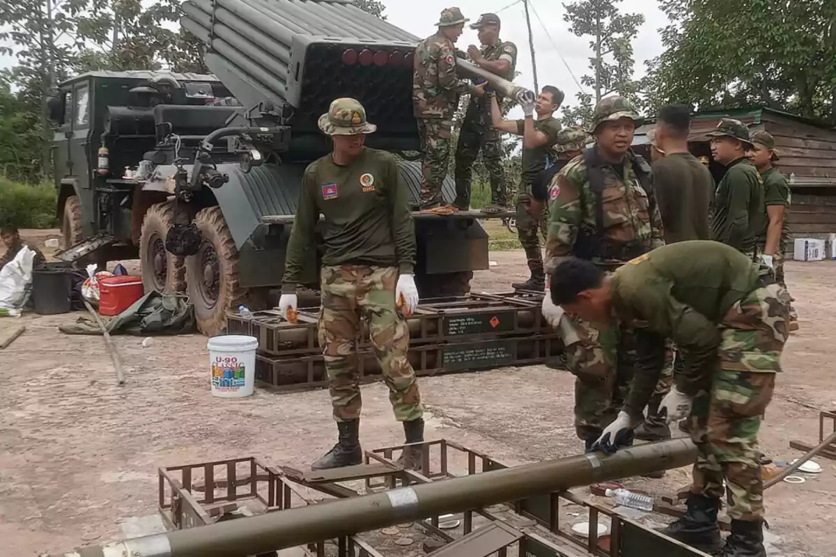 Soldados con uniforme de camuflaje preparan y cargan cohetes en un vehículo militar en una zona al aire libre rodeada de árboles. Soldados con uniforme de camuflaje preparan y cargan cohetes en un vehículo militar en una zona al aire libre rodeada de árboles.