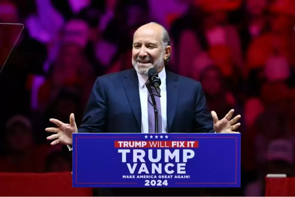 Man in a suit speaking at a political rally with a sign that says Trump Vance 2024 Make America Great Again Man in a suit speaking at a political rally with a sign that says Trump Vance 2024 Make America Great Again