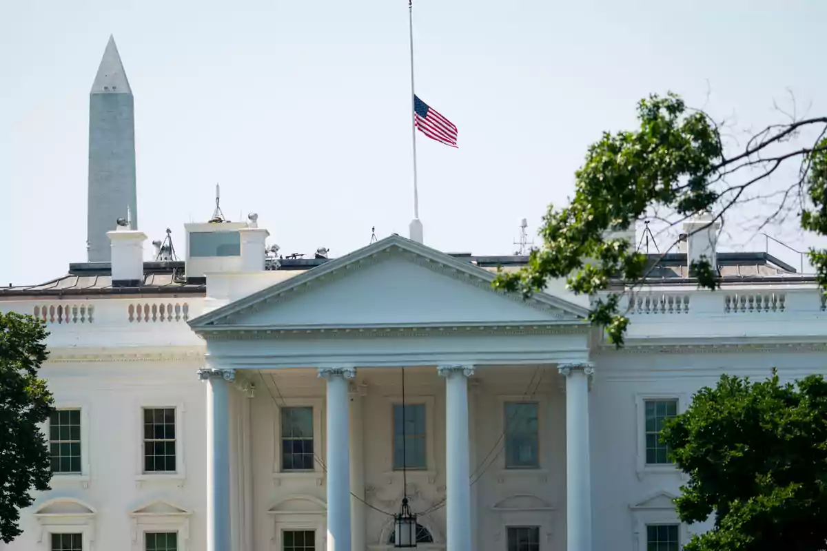 The White House with the United States flag at half-mast and the Washington Monument in the background The White House with the United States flag at half-mast and the Washington Monument in the background
