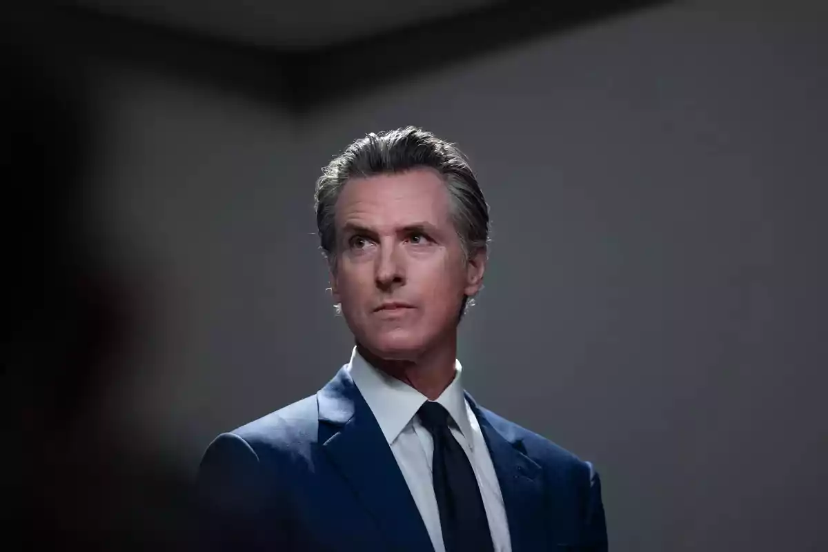 Gray-haired man in a blue suit and dark tie looking to the side in a room with a gray background Gray-haired man in a blue suit and dark tie looking to the side in a room with a gray background
