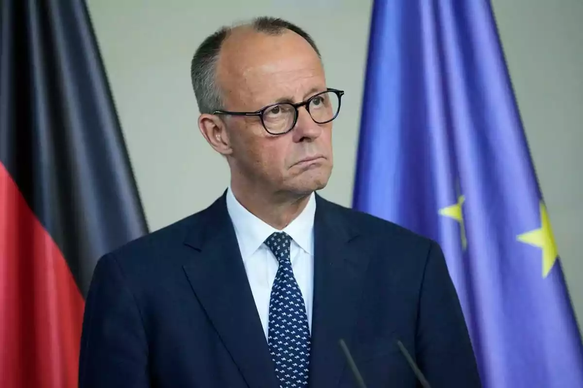 Man in a suit and glasses standing in front of the flags of Germany and the European Union Man in a suit and glasses standing in front of the flags of Germany and the European Union
