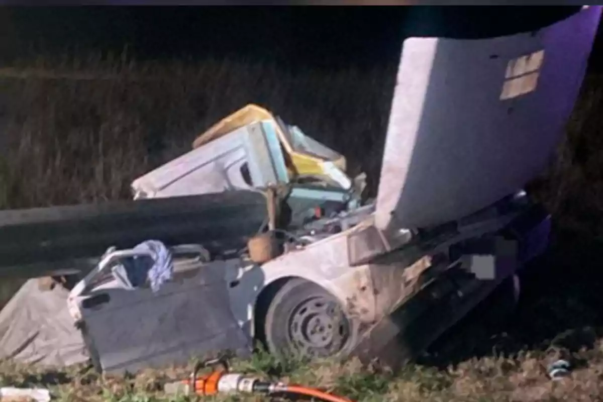 Auto blanco gravemente dañado tras chocar contra un poste en una zona de pasto durante la noche