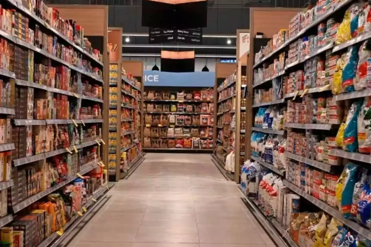 Pasillo de supermercado con estantes llenos de productos empaquetados a ambos lados