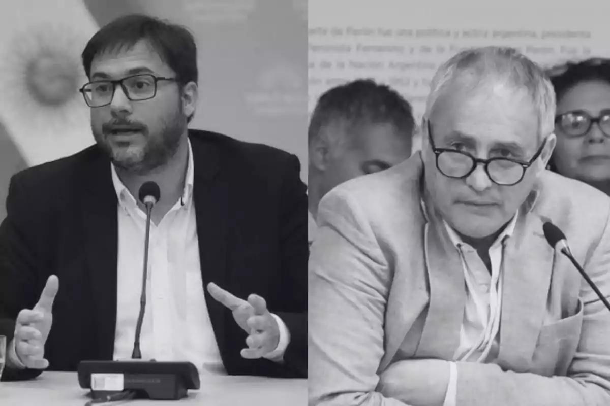 Dos hombres con gafas y saco sentados frente a micrófonos en una conferencia o reunión