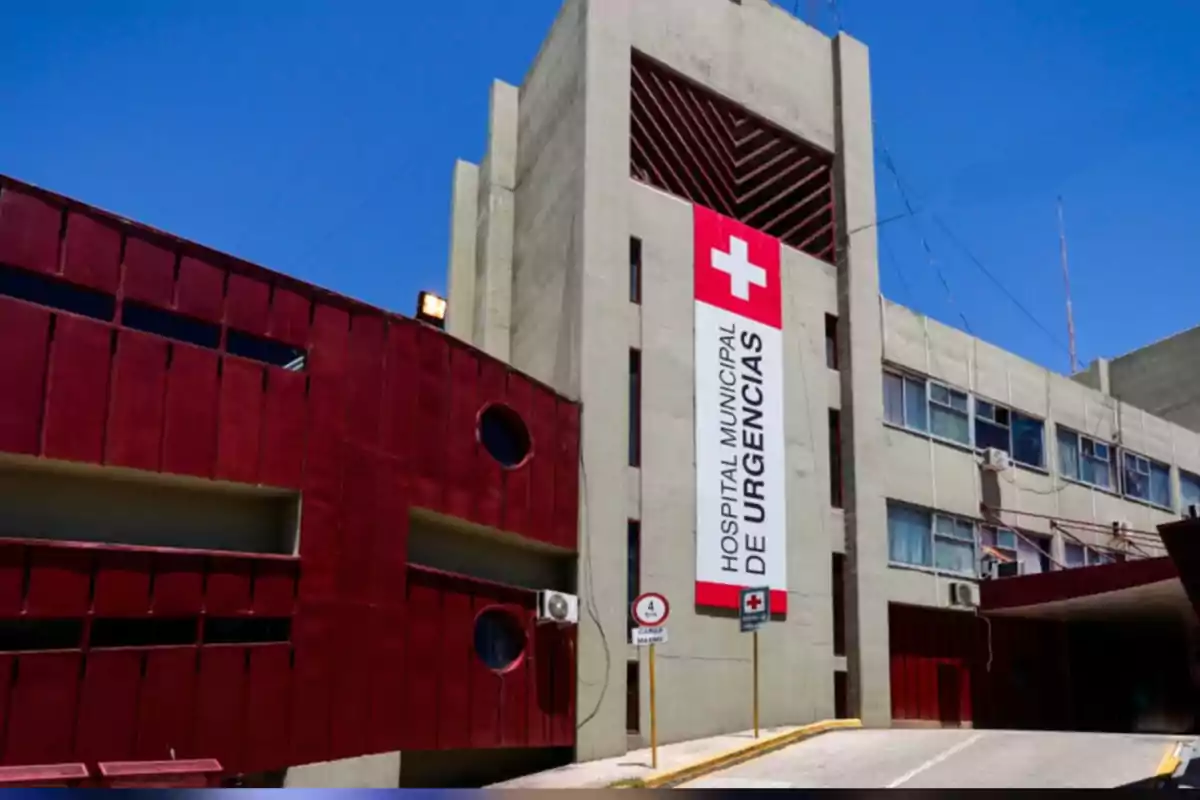 Fachada de un hospital municipal de urgencias con paredes grises y detalles en rojo bajo un cielo despejado Fachada de un hospital municipal de urgencias con paredes grises y detalles en rojo bajo un cielo despejado