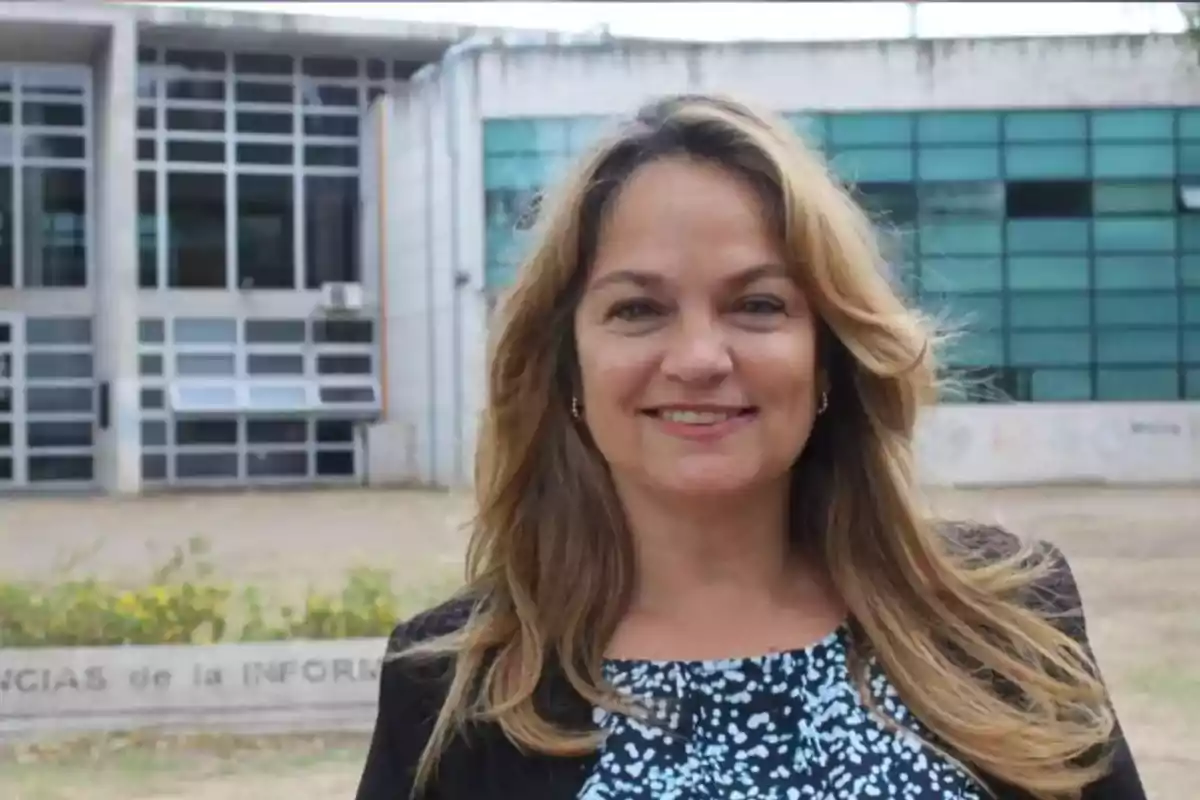 Smiling blonde woman posing outdoors in front of a modern building with large windows Smiling blonde woman posing outdoors in front of a modern building with large windows