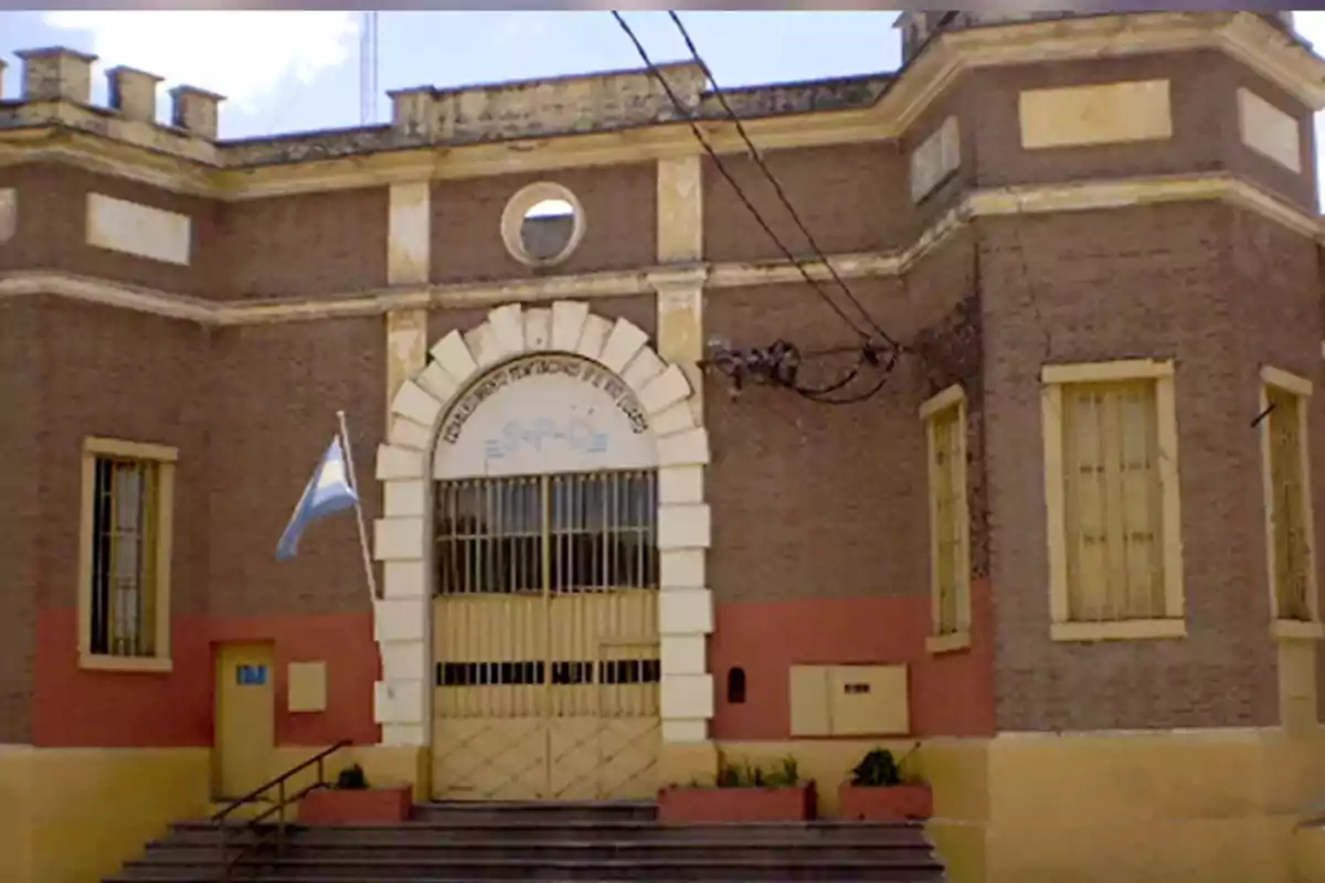Fachada de un edificio antiguo de ladrillo con rejas en las ventanas y una bandera argentina ondeando a la izquierda Fachada de un edificio antiguo de ladrillo con rejas en las ventanas y una bandera argentina ondeando a la izquierda