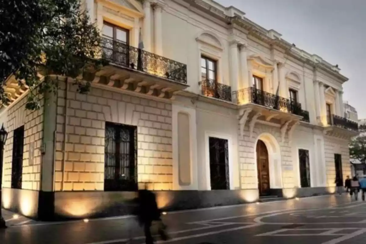 Old two-story building with wrought iron balconies and large windows illuminated by exterior lights on a pedestrian street Old two-story building with wrought iron balconies and large windows illuminated by exterior lights on a pedestrian street