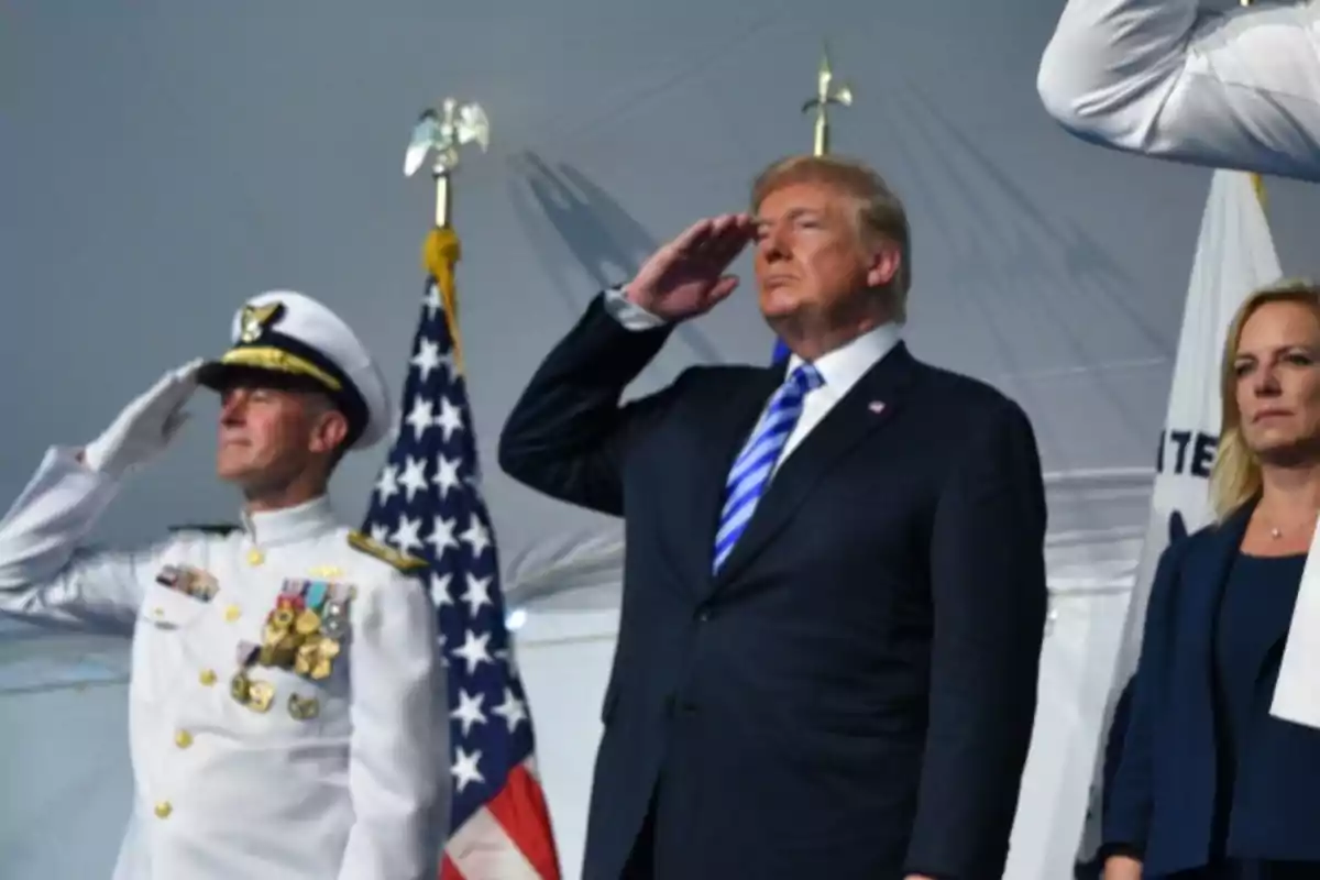 People standing and performing a military salute in front of United States flags at an official event