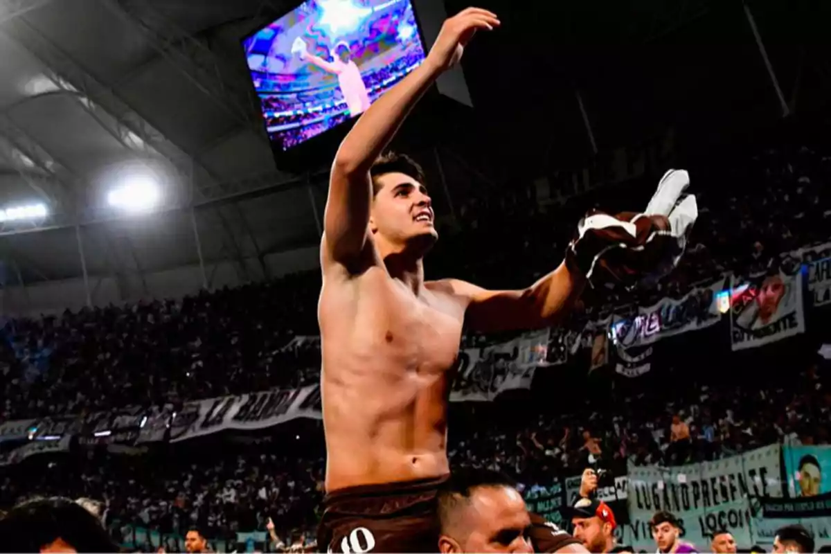 Soccer player celebrating jerseyless in front of a crowd in a packed stadium at night Soccer player celebrating jerseyless in front of a crowd in a packed stadium at night