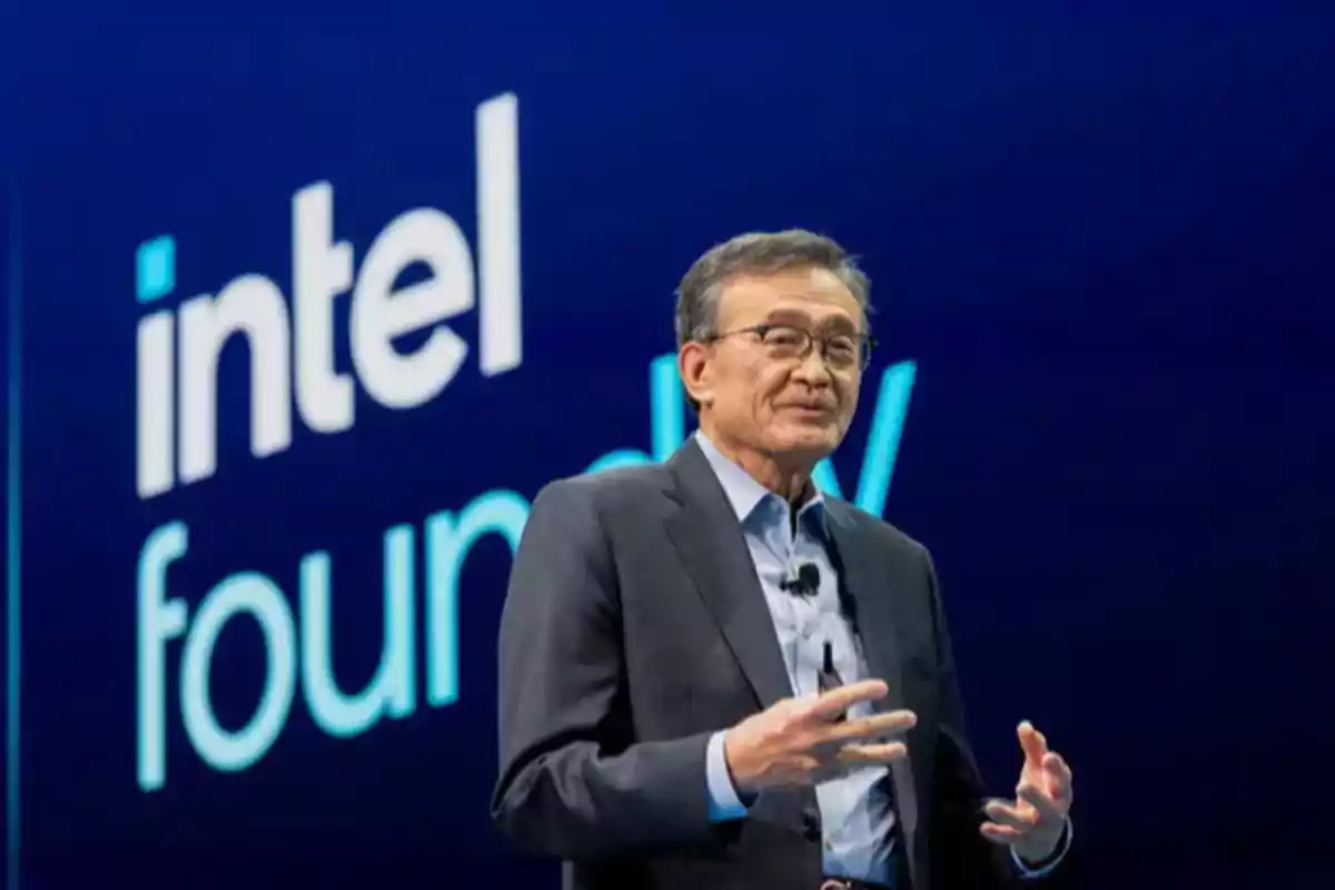 Man in a suit speaking on a stage with the Intel Foundry logo in the background Man in a suit speaking on a stage with the Intel Foundry logo in the background