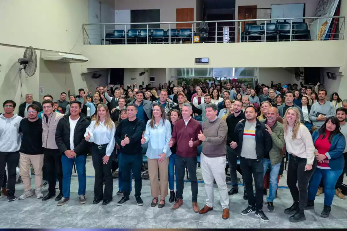 Un grupo numeroso de personas posando y sonriendo para una foto en el interior de un auditorio