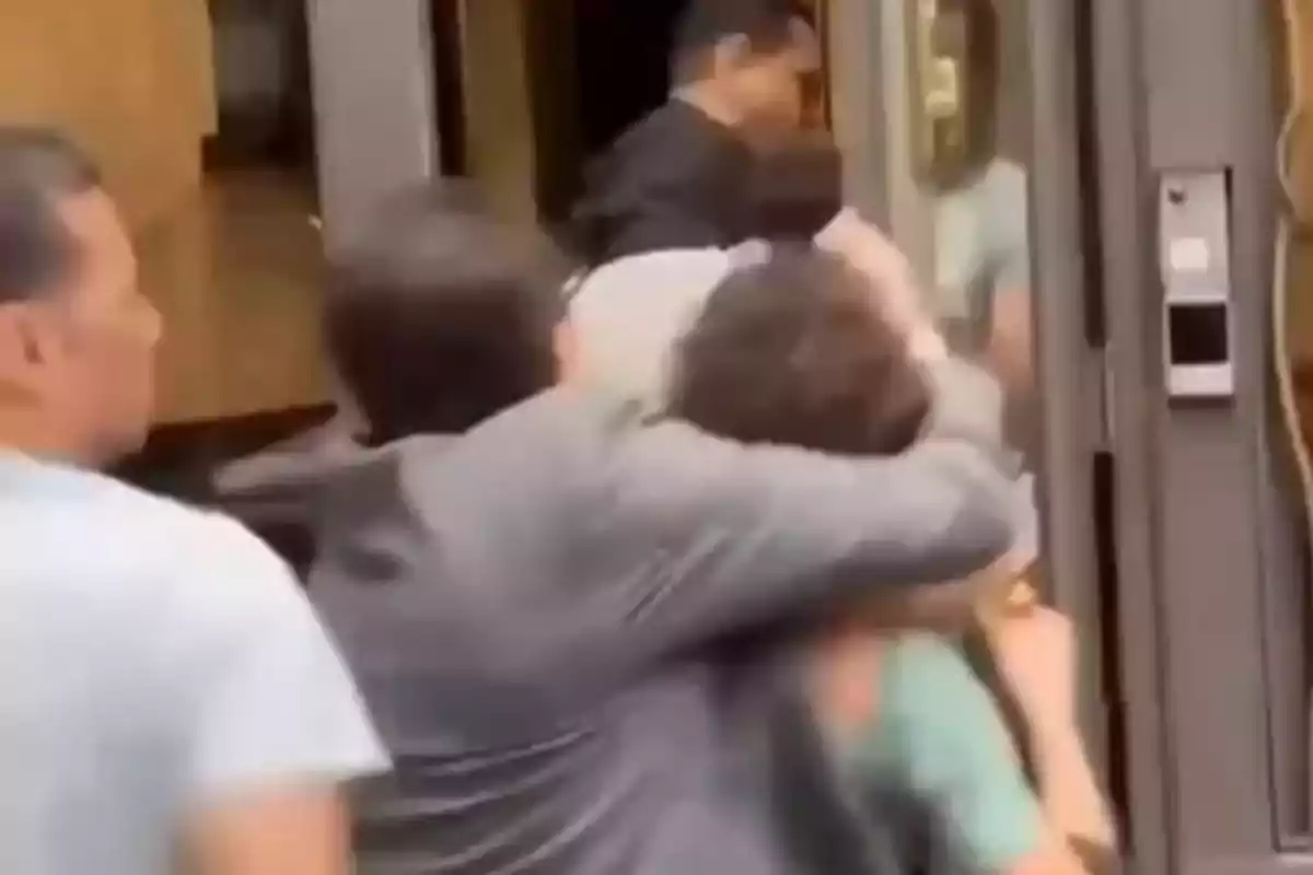 Several people struggle near a door while one of them holds another by the neck. Several people struggle near a door while one of them holds another by the neck.