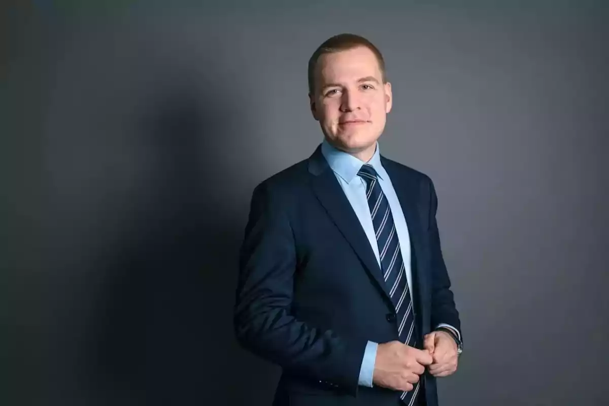 Young man in a blue suit and striped tie posing in front of a gray background