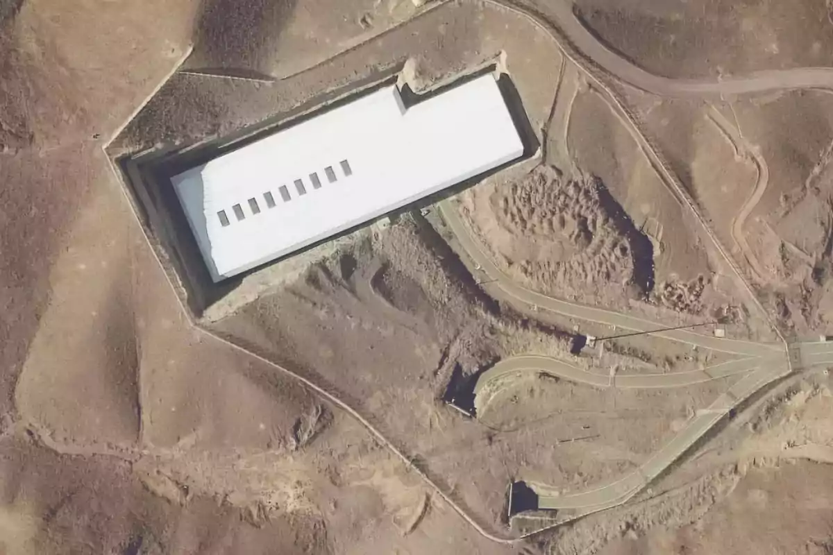 Aerial view of a white rectangular building surrounded by roads and arid land Aerial view of a white rectangular building surrounded by roads and arid land