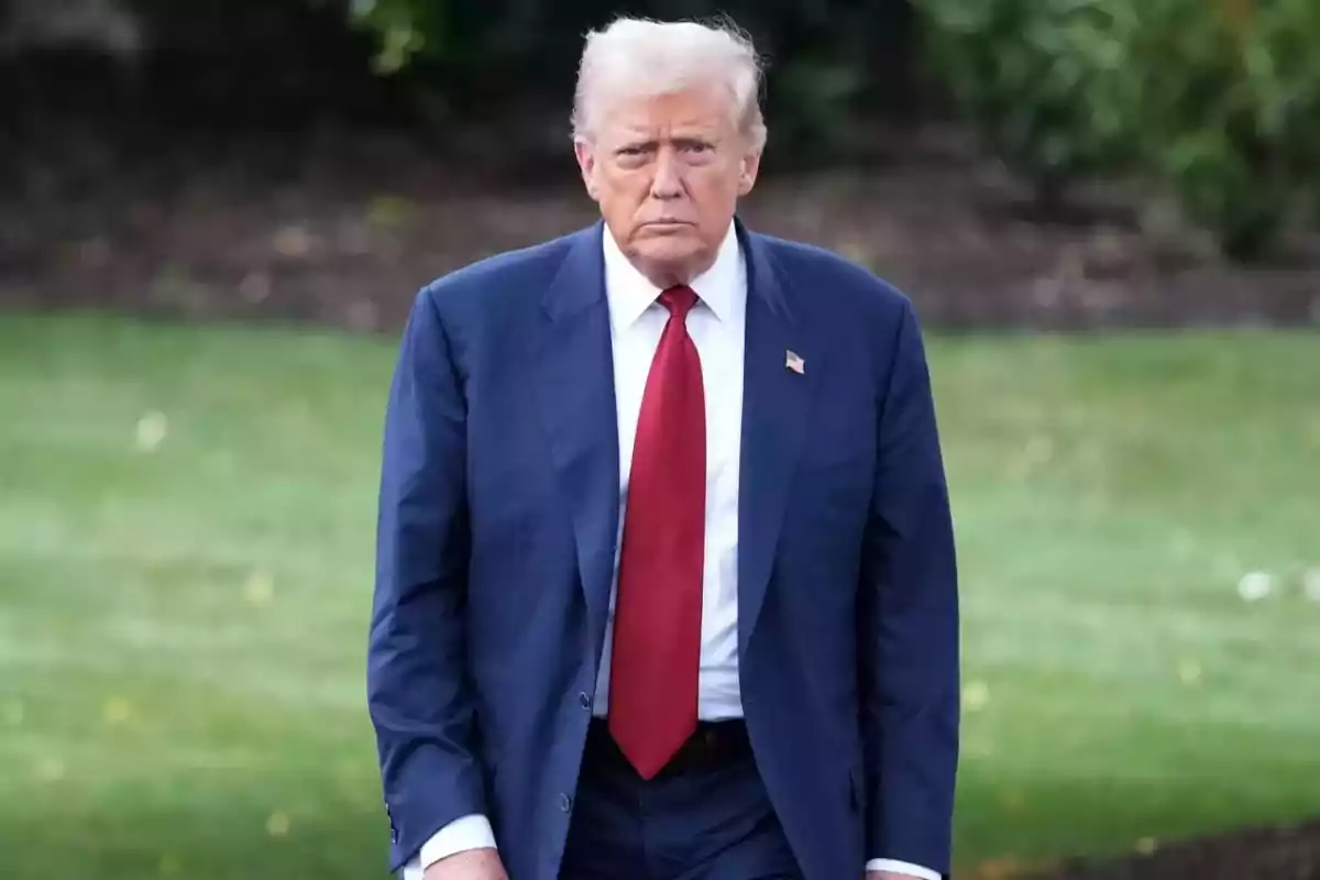 Blond-haired man in a blue suit and red tie walking in a garden Blond-haired man in a blue suit and red tie walking in a garden