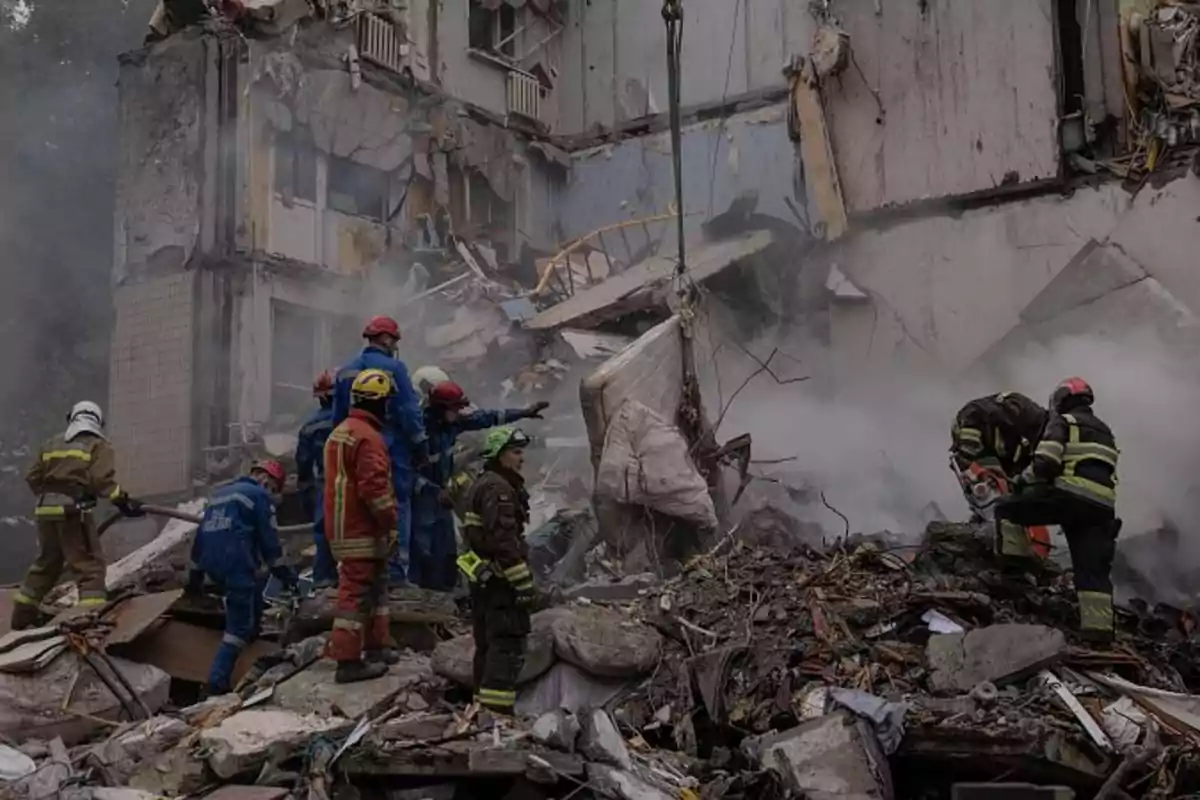 Several rescuers work among the rubble of a collapsed building covered in dust and smoke. Several rescuers work among the rubble of a collapsed building covered in dust and smoke.