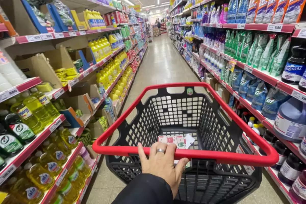 Persona empujando un carrito de compras en el pasillo de productos de limpieza de un supermercado Persona empujando un carrito de compras en el pasillo de productos de limpieza de un supermercado
