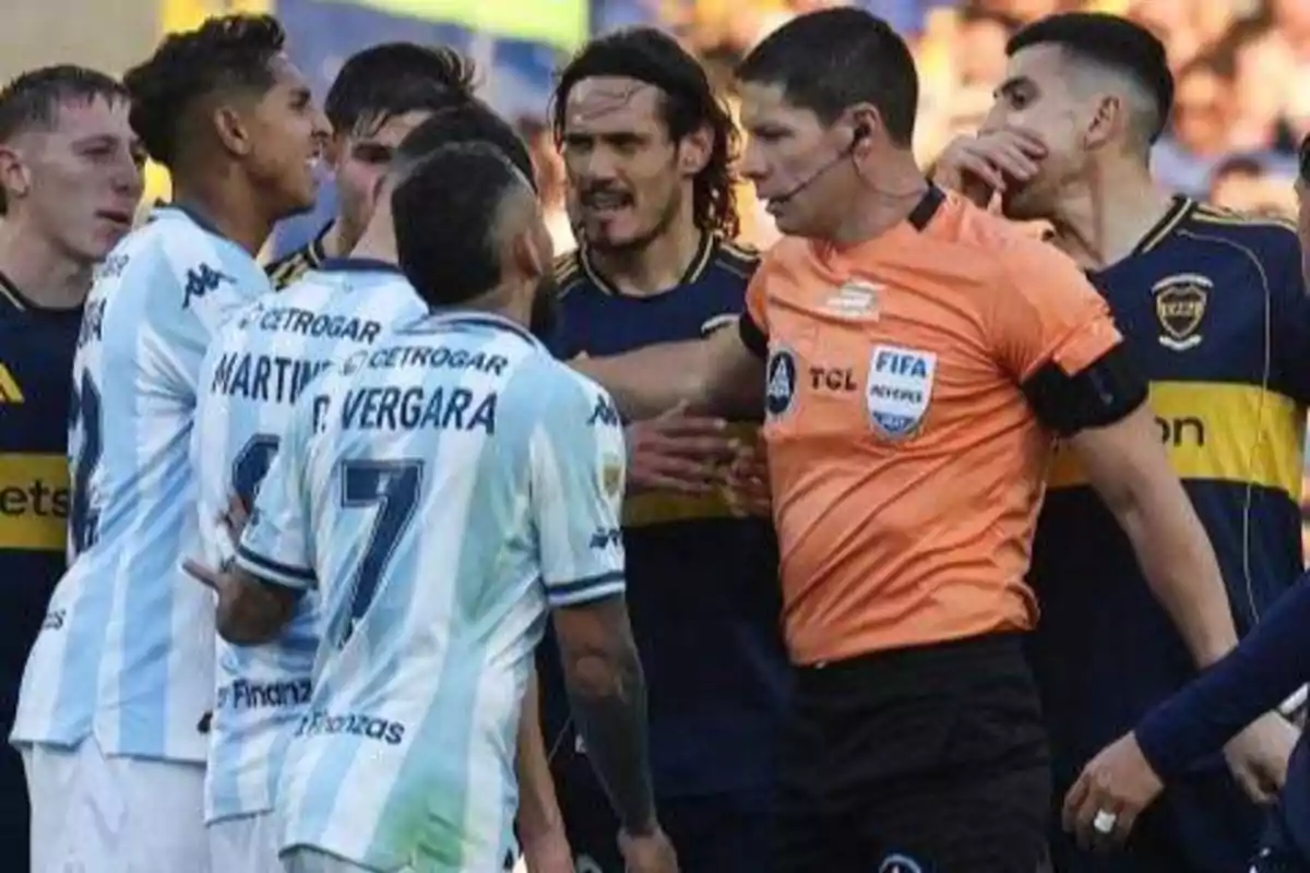 Jugadores de dos equipos de fútbol discuten acaloradamente mientras el árbitro intenta separarlos durante un partido