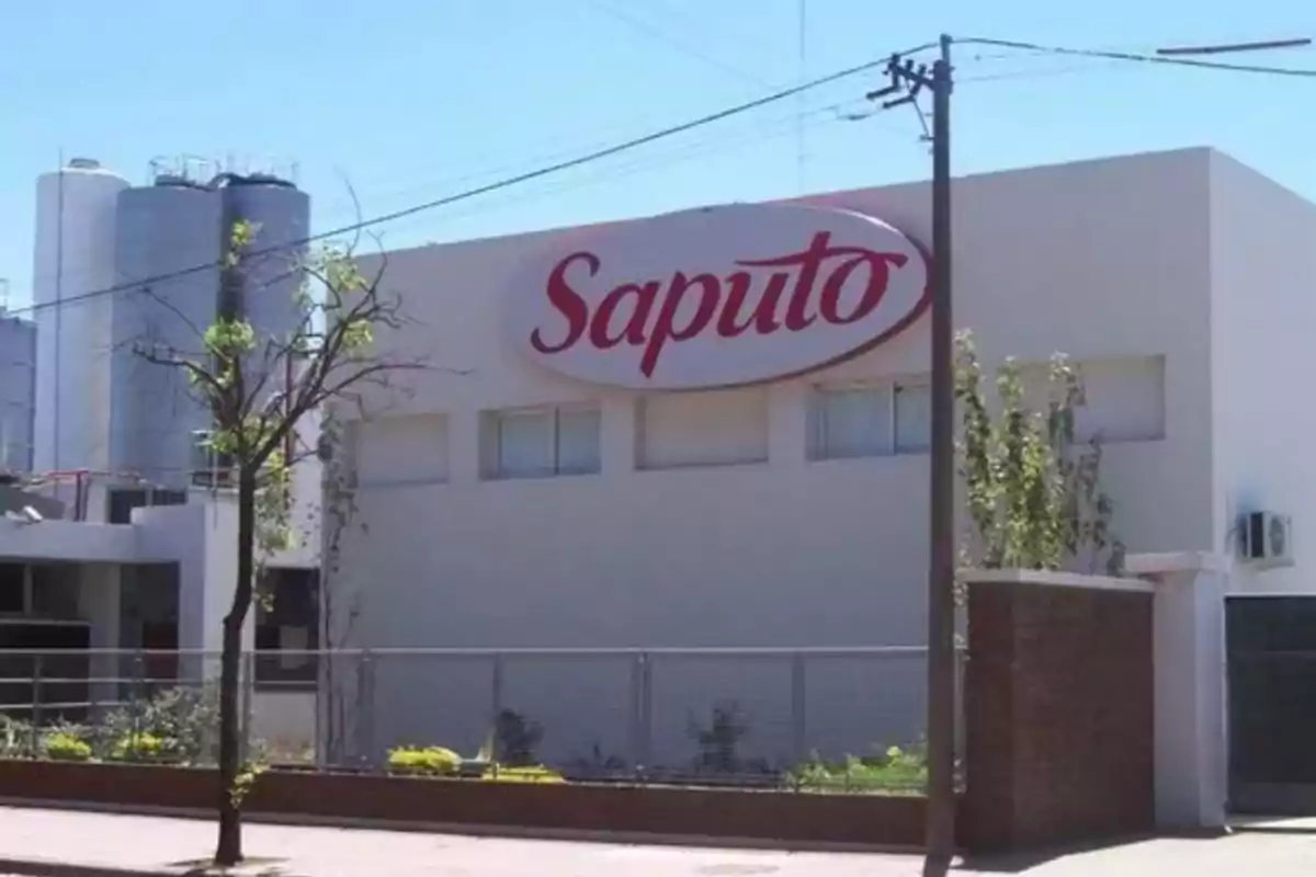 Fachada de una planta industrial con el logo de Saputo en un cartel grande sobre la pared principal Fachada de una planta industrial con el logo de Saputo en un cartel grande sobre la pared principal