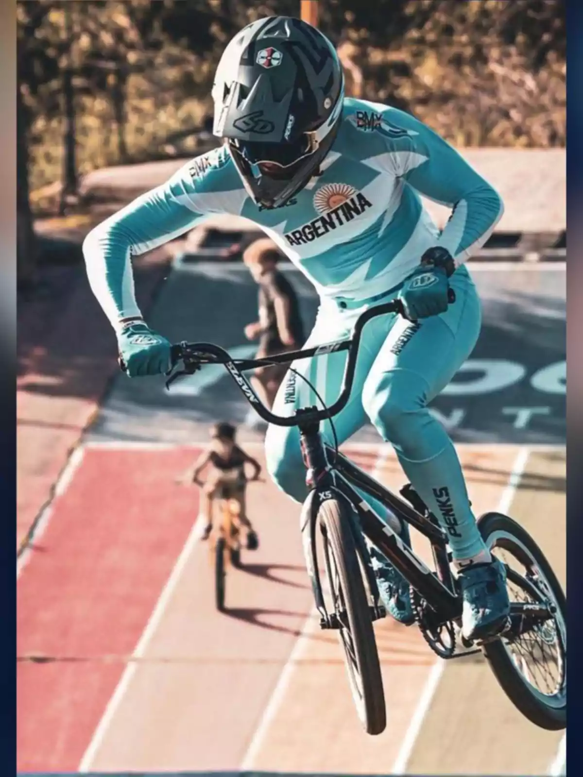 Cyclist in a light blue Argentina uniform performing a jump on a BMX track during a competition Cyclist in a light blue Argentina uniform performing a jump on a BMX track during a competition