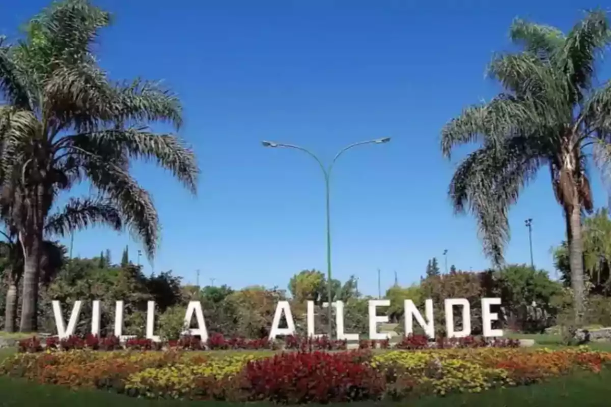 Villa Allende sign surrounded by palm trees and flowers under a clear sky Villa Allende sign surrounded by palm trees and flowers under a clear sky
