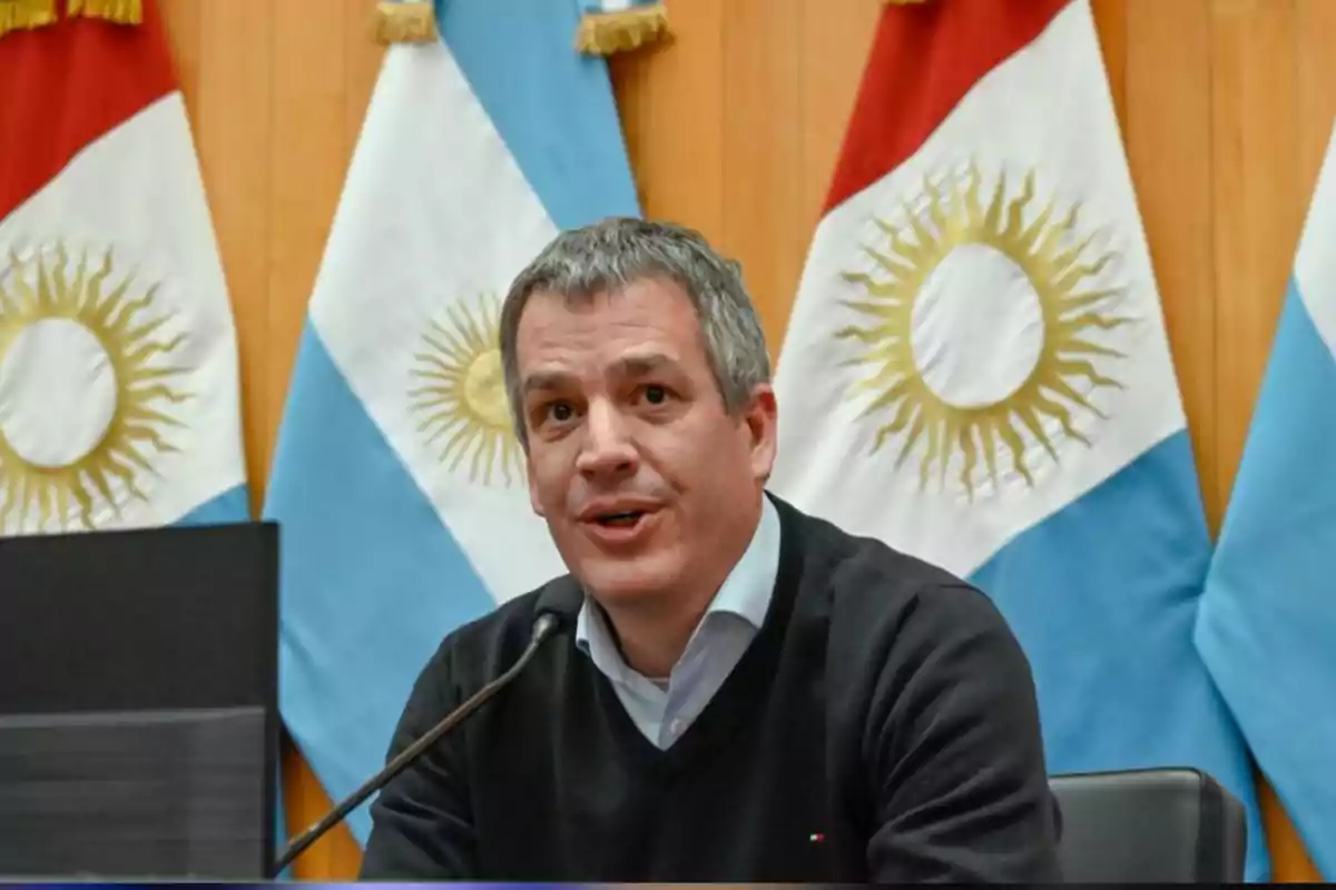 Man speaking in front of a microphone with Argentine flags in the background Man speaking in front of a microphone with Argentine flags in the background