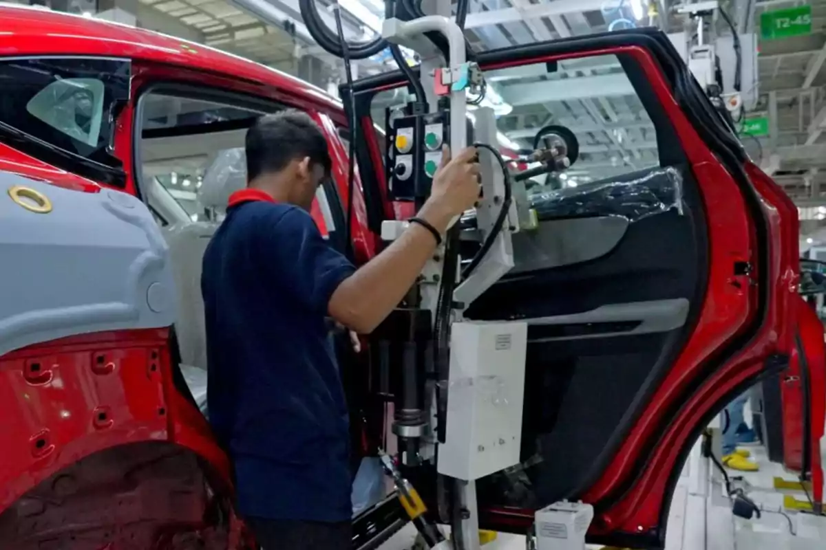 Worker assembling the door of a red car on an industrial production line Worker assembling the door of a red car on an industrial production line