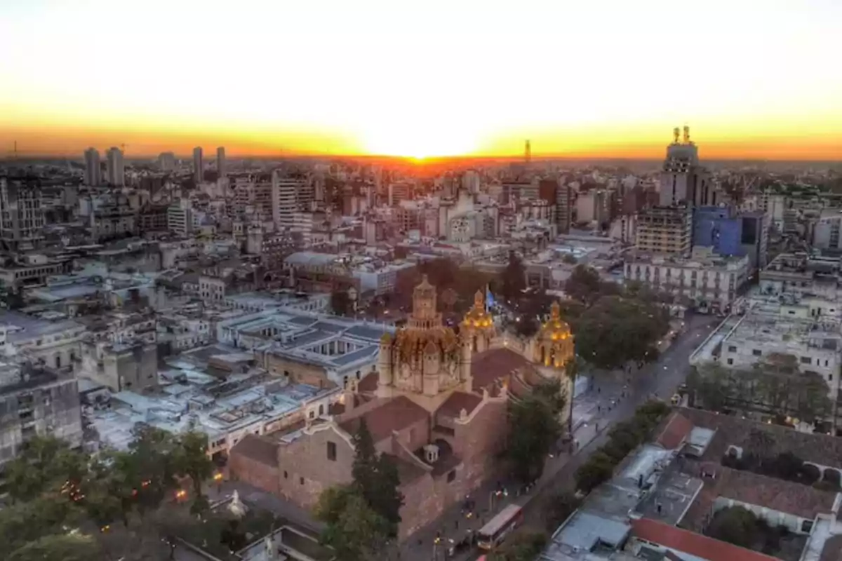 Aerial view of a city at sunset with a colonial church in the foreground and modern buildings in the background Aerial view of a city at sunset with a colonial church in the foreground and modern buildings in the background
