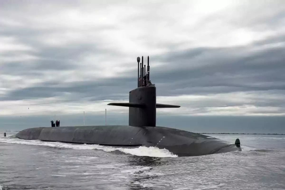 Submarine sailing on the surface of the sea under a cloudy sky with several people standing on the deck Submarine sailing on the surface of the sea under a cloudy sky with several people standing on the deck