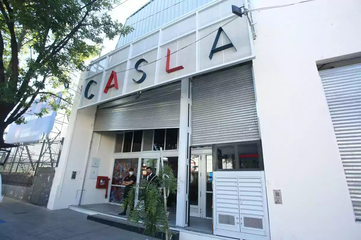Facade of a building with the letters CASLA at the top and two people at the entrance