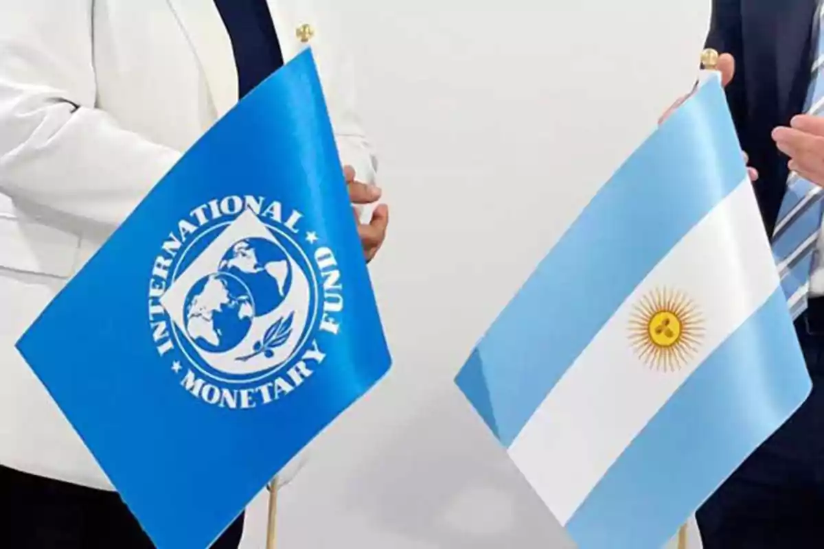Two people hold the flags of the International Monetary Fund and Argentina at a formal meeting. Two people hold the flags of the International Monetary Fund and Argentina at a formal meeting.