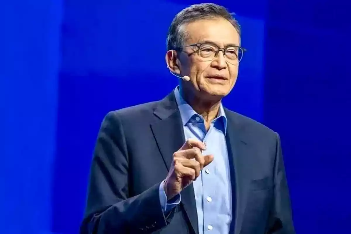 Middle-aged man with glasses and a headset microphone speaking on a stage with a blue background Middle-aged man with glasses and a headset microphone speaking on a stage with a blue background