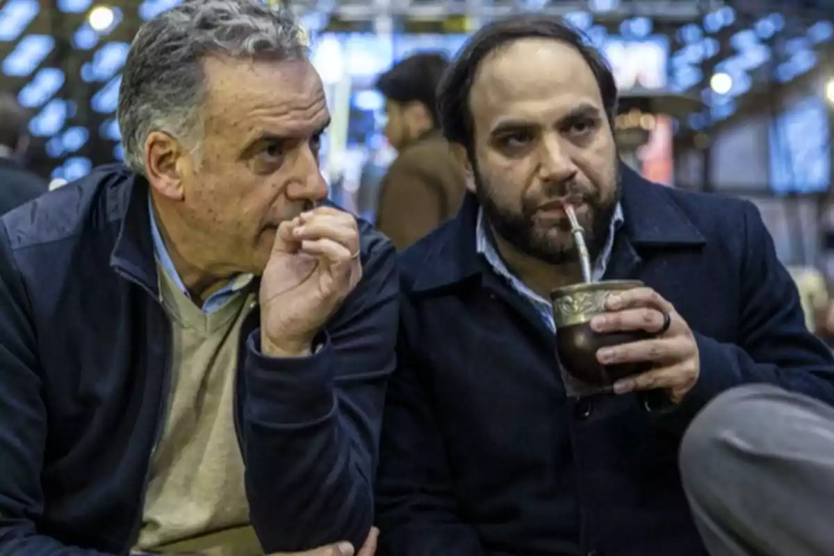 Two men sitting and talking, one of them holding a mate and drinking it. Two men sitting and talking, one of them holding a mate and drinking it.