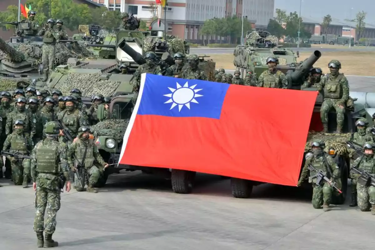 Soldiers in camouflage uniforms and military gear pose next to armored vehicles holding a large Taiwanese flag.