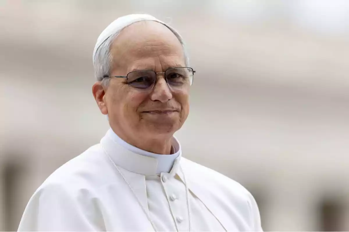 Older man with glasses and white religious clothing smiles slightly outdoors Older man with glasses and white religious clothing smiles slightly outdoors