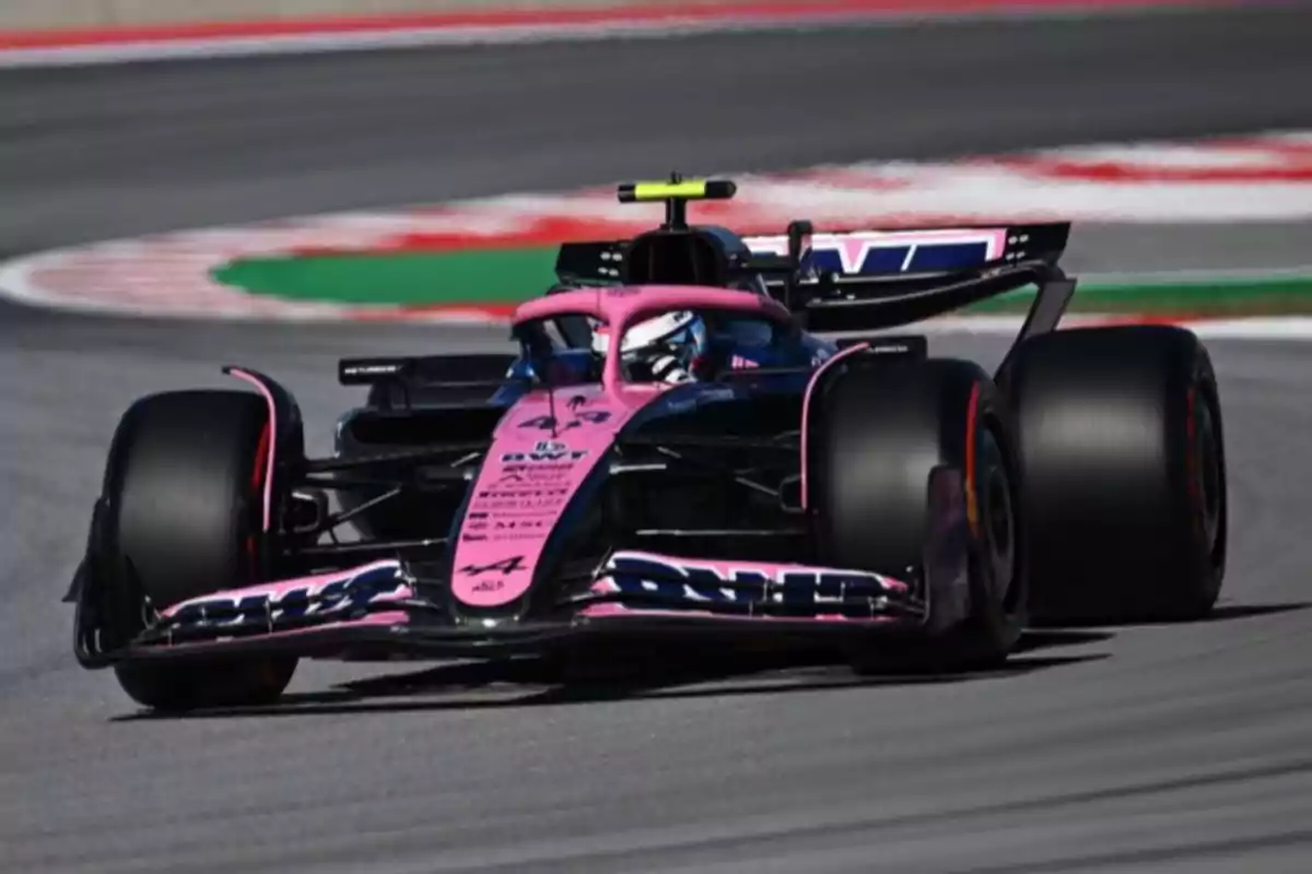 Pink and black Formula 1 car taking a corner on a racetrack