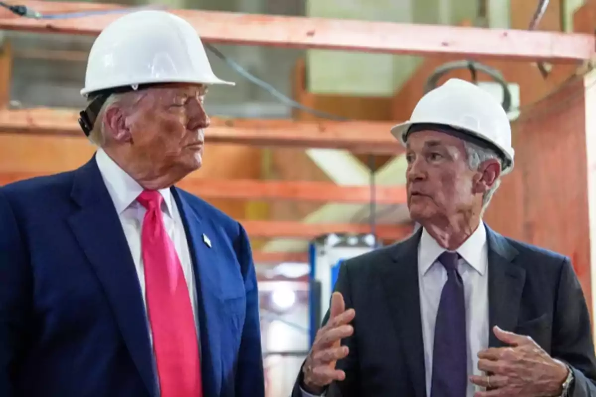 Dos hombres con casco de seguridad conversan en lo que parece ser una construcción, ambos llevan traje y corbata Dos hombres con casco de seguridad conversan en lo que parece ser una construcción, ambos llevan traje y corbata