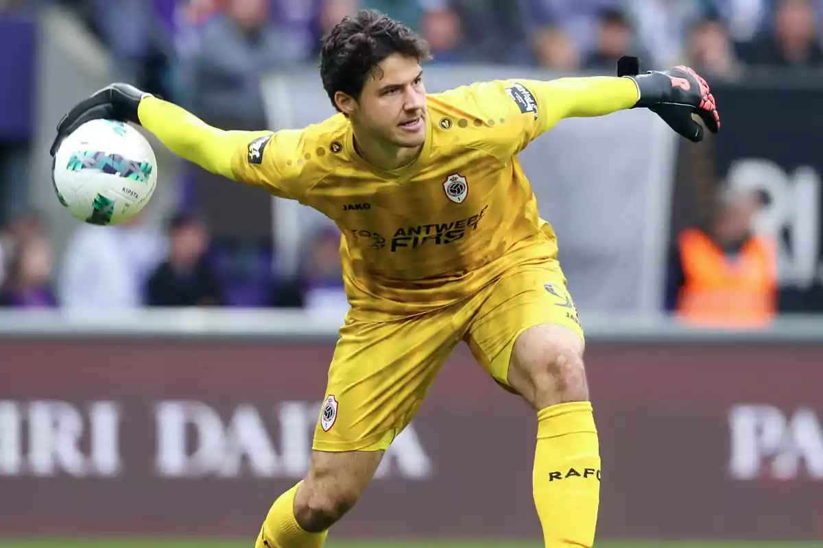 Portero de fútbol con uniforme amarillo lanzando el balón con una mano durante un partido Portero de fútbol con uniforme amarillo lanzando el balón con una mano durante un partido