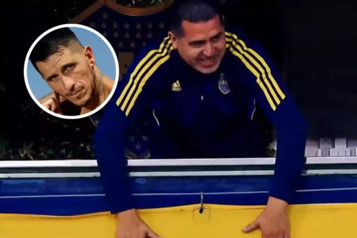 Man in a blue and yellow jacket leaning on a railing with a soccer crest in the background and a box with another man's face in the top left corner