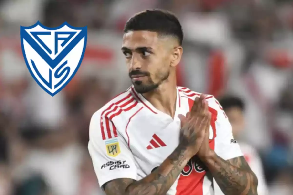 Soccer player in a River Plate uniform applauding with the Vélez Sarsfield crest in the background