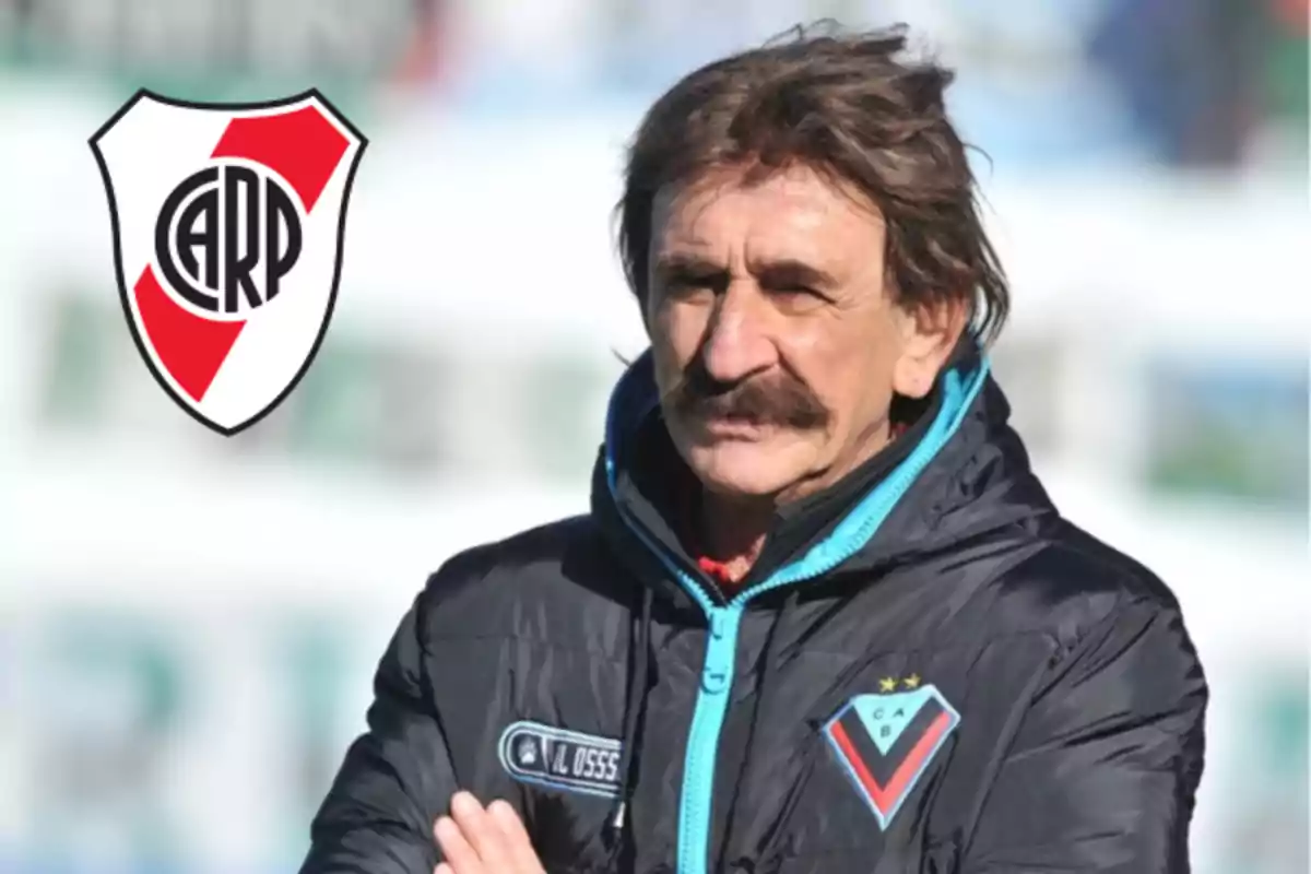 Mustached man wearing a sports jacket from a Bolivian club with the River Plate crest in the background