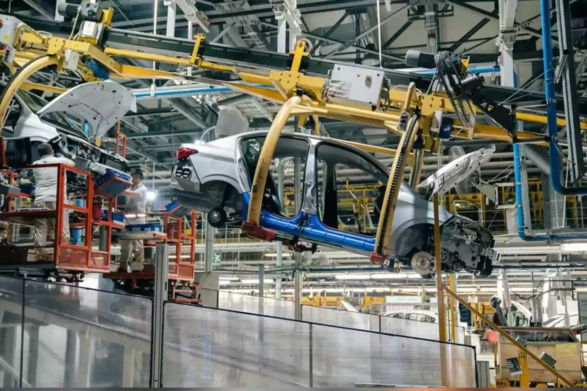 Línea de ensamblaje de automóviles en una fábrica con trabajadores y maquinaria industrial