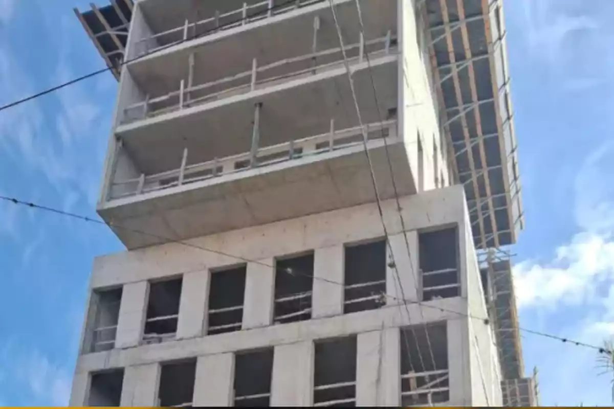 Edificio en construcción con varios pisos y andamios bajo un cielo azul Edificio en construcción con varios pisos y andamios bajo un cielo azul