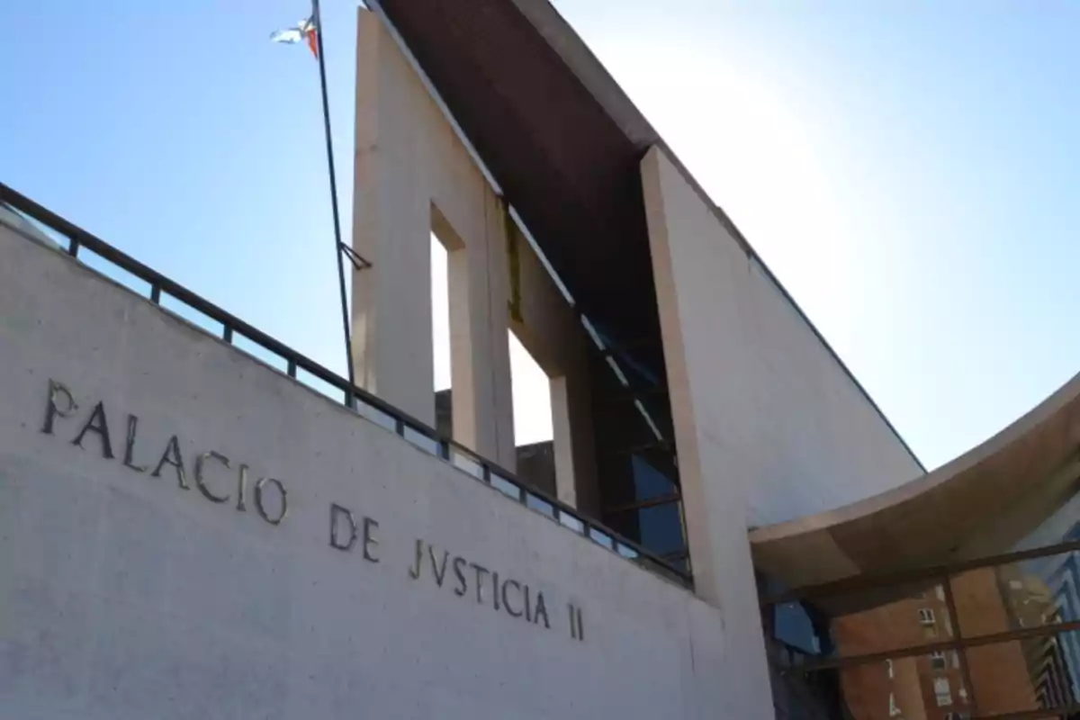 Fachada moderna de un edificio de justicia con letras que dicen Palacio de Justicia II y una bandera ondeando en la parte superior Fachada moderna de un edificio de justicia con letras que dicen Palacio de Justicia II y una bandera ondeando en la parte superior