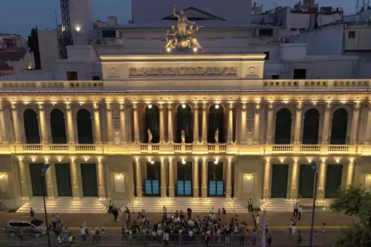 Facade of a theater illuminated at dusk with people gathered at the entrance Facade of a theater illuminated at dusk with people gathered at the entrance