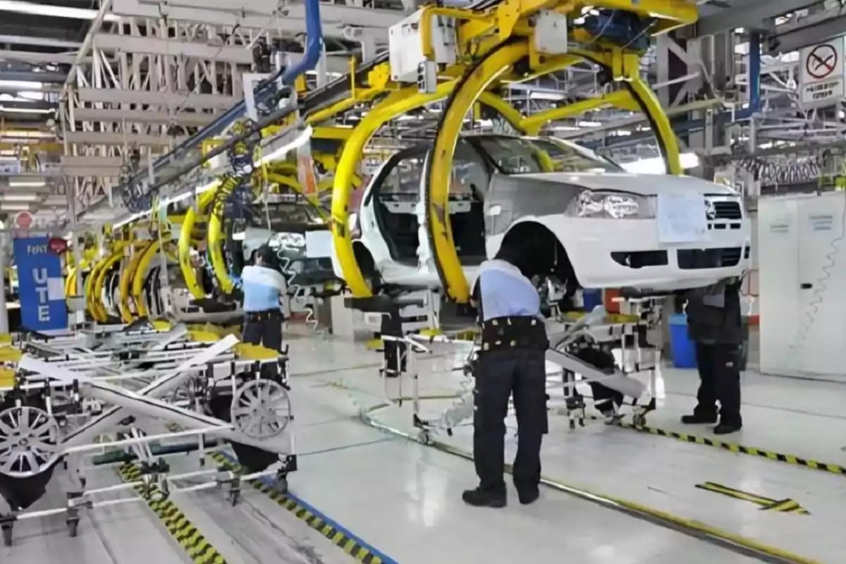 Workers assembling automobiles on a production line inside an industrial factory Workers assembling automobiles on a production line inside an industrial factory