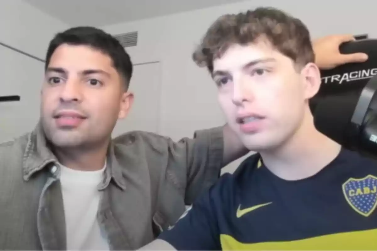 Two young people sitting together looking at a screen with alert expressions, one of them wearing a blue and yellow soccer jersey. Two young people sitting together looking at a screen with alert expressions, one of them wearing a blue and yellow soccer jersey.